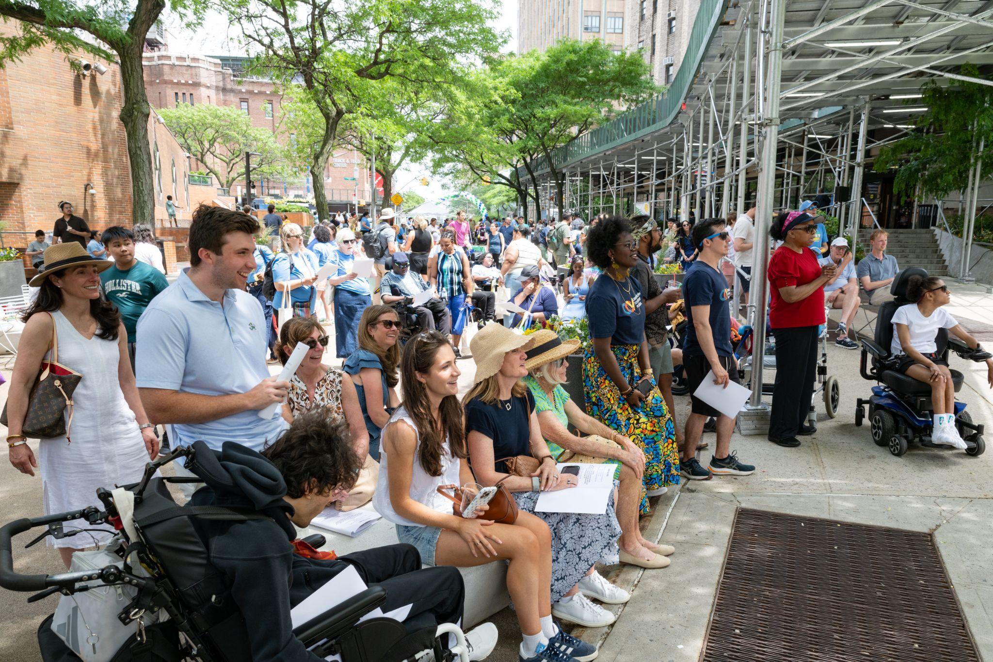 A large crowd of community members, several using wheelchairs, gathered along the plaza at CP Community Day